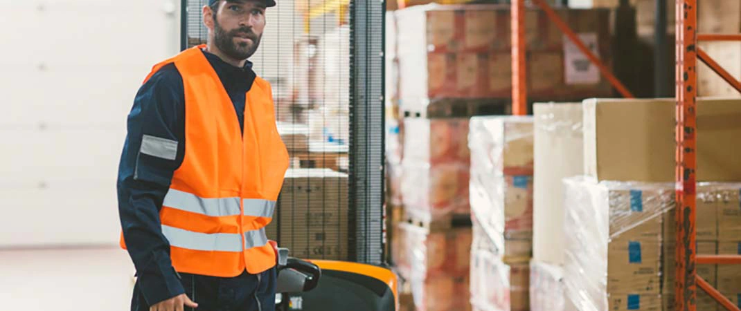 Mann bedient batteriebetriebenen Hochhubwagen im Lager